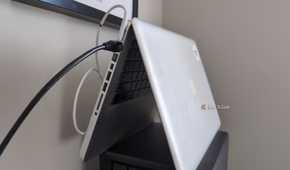 An old MacBook laptop stood in the tent position with an Ethernet cable plugged into it.