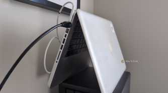 An old MacBook laptop stood in the tent position with an Ethernet cable plugged into it.