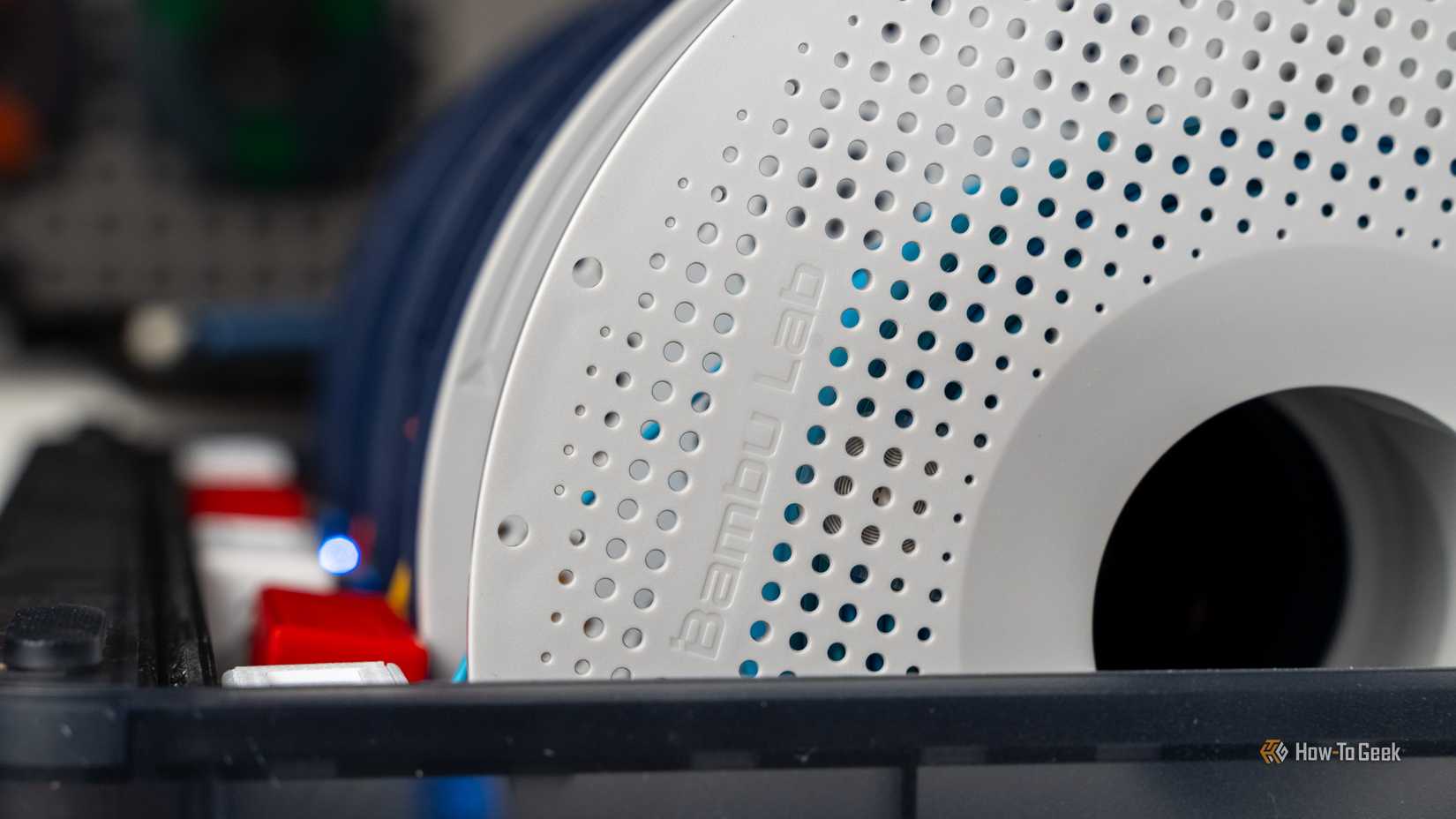 Close-up of the embossed Bambu Lab logo on a filament spool inside an AMS unit.