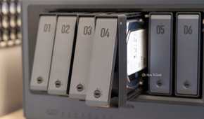 Drive trays fanned out from the Ugreen iDX6011 Pro NAS showing the tool-free tray design and an installed hard drive.