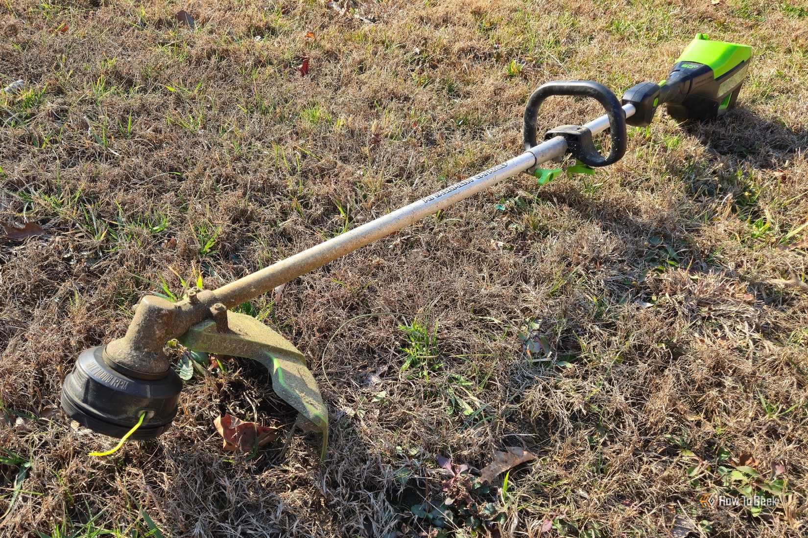Greenworks 60V 16-inch string trimmer lying on grass.