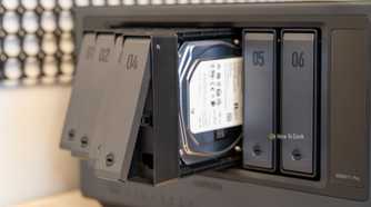 Multiple drive trays pulled out from the Ugreen iDX6011 Pro NAS with a hard drive visible inside the bay.