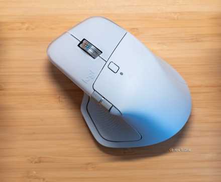 The Logitech MX Master 4 on a wooden desk between two halves of a split mechanical keyboard.