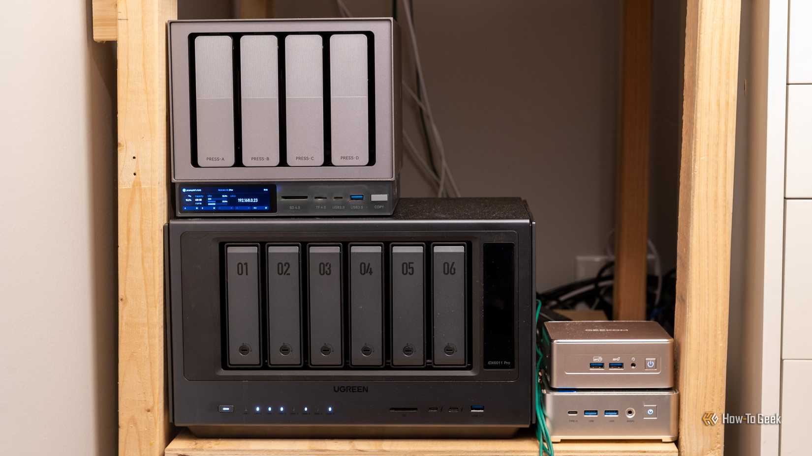 Ugreen NAS and Geekom mini PCs on a wooden homelab shelf.