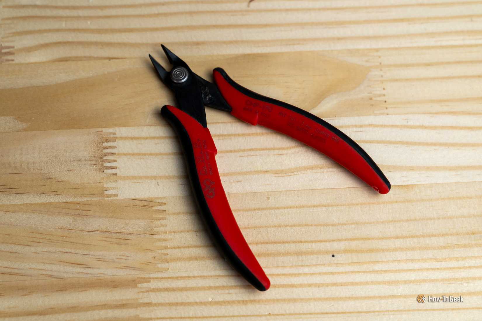 A pair of red and black flush cutters resting on a wooden workbench.