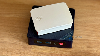 A Raspberry Pi in a case lying on top of a Beelink Mini S12 Pro mini PC.