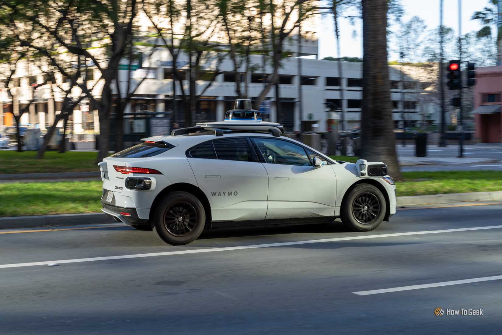 A Waymo self-driving Jaguar I-PACE SUV driving down a city street.