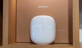 A white Nest Wifi Pro router displayed on a wooden shelf.