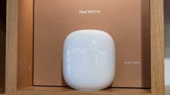 A white Nest Wifi Pro router displayed on a wooden shelf.