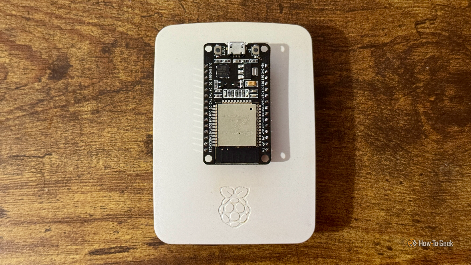 An ESP32 lying on top of a Raspberry Pi in a case.
