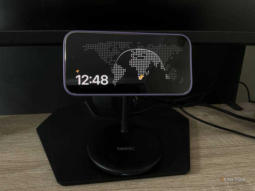An iPhone showing a world clock sits no a desk.