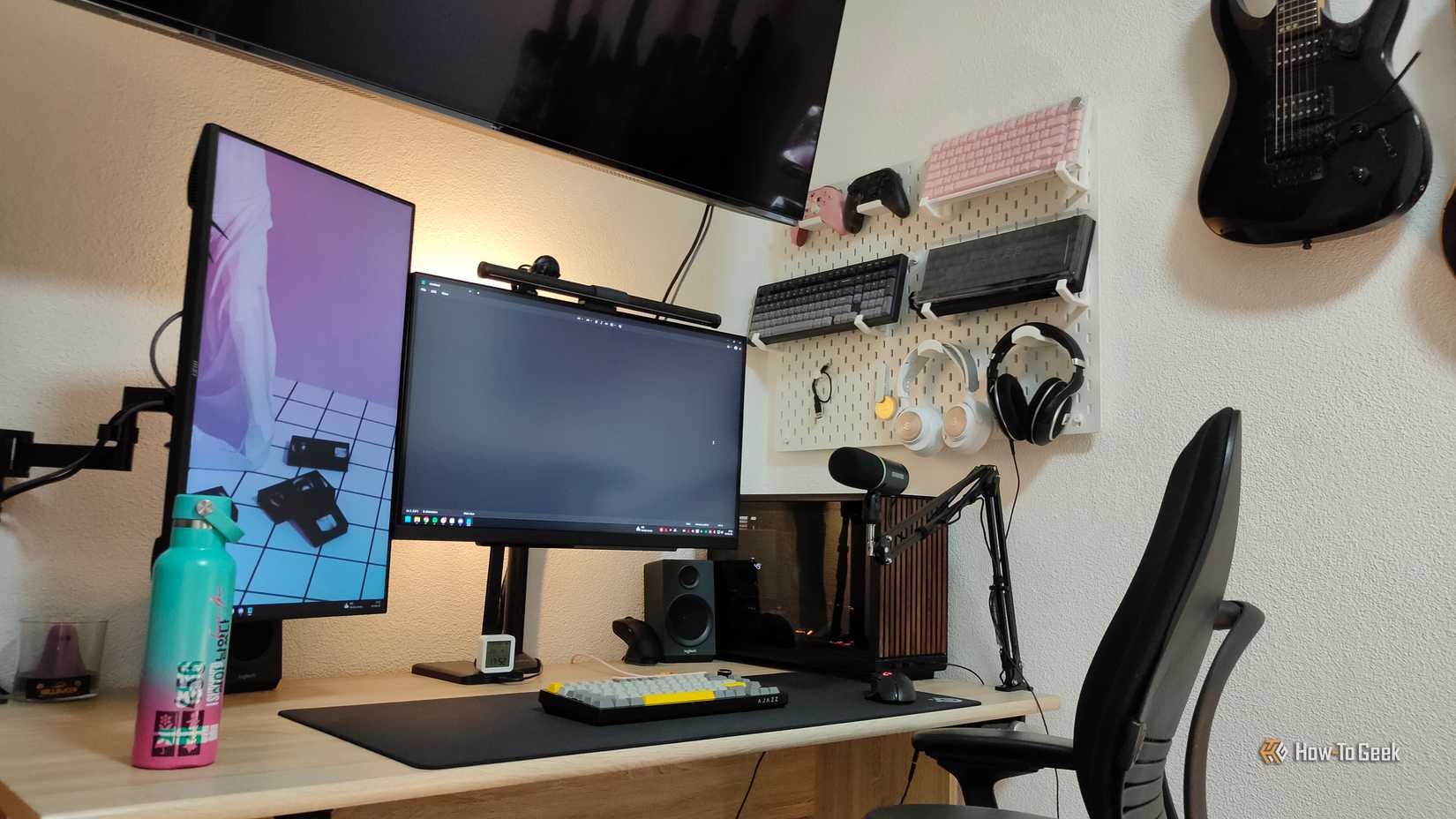 Desk setup with monitors, TV, and pegboard (2)