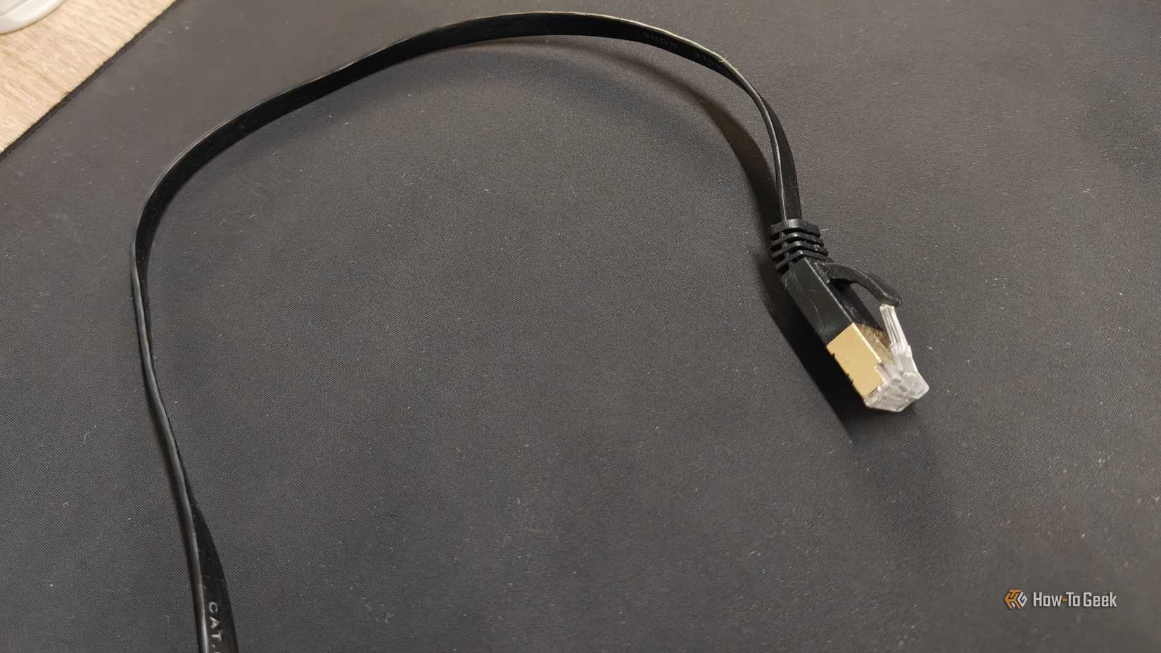 A flat Cat6 Ethernet cable on a black mousepad.