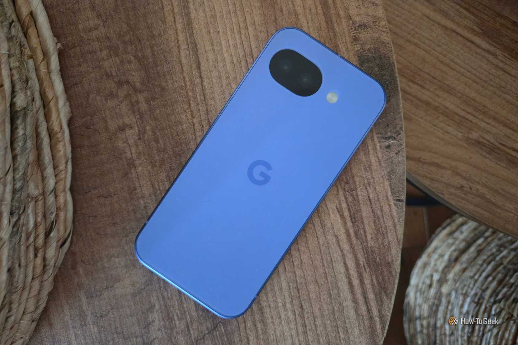 Google Pixel 10a lying facedown on a table with two baskets in the background.
