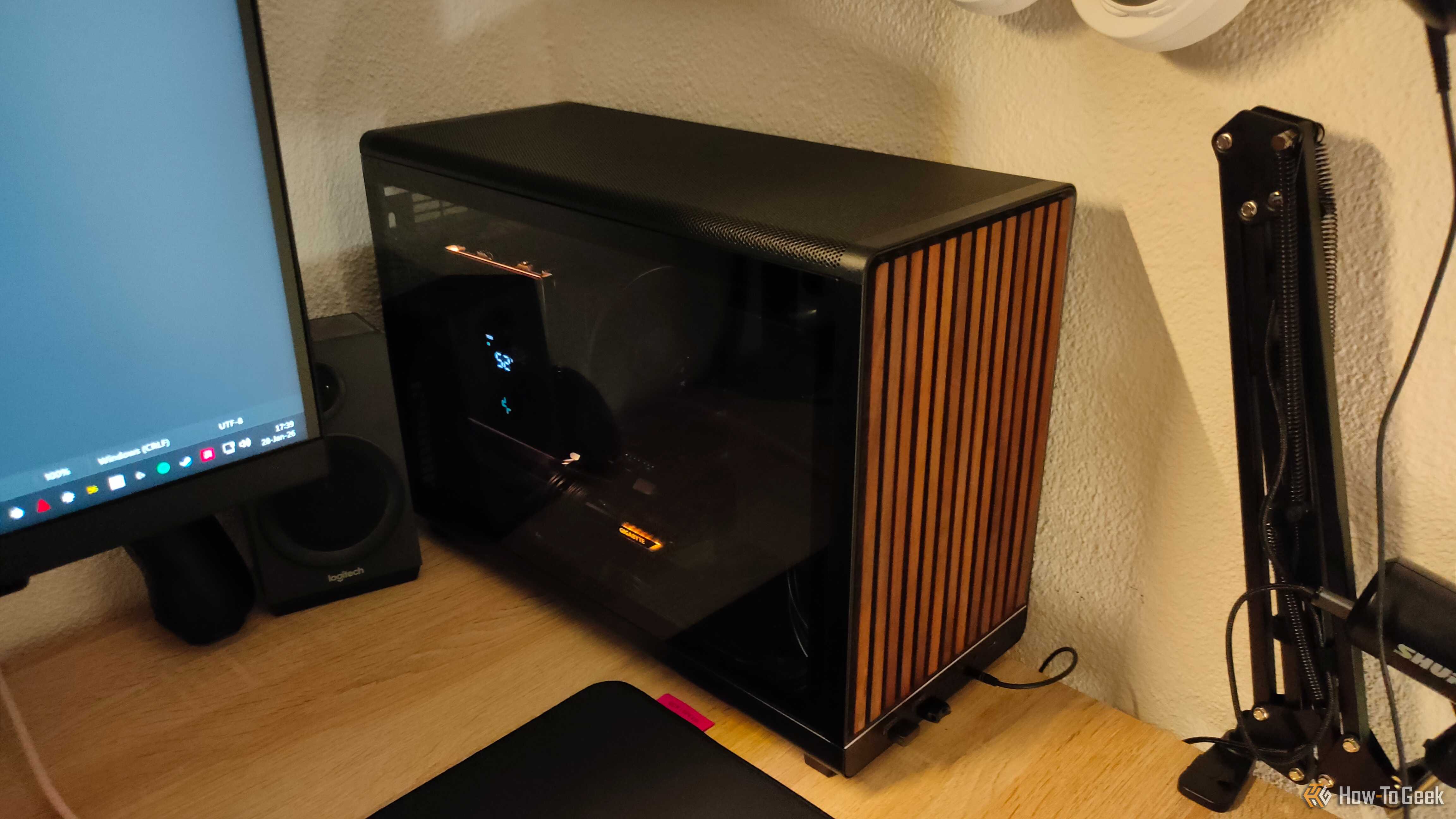 An ITX PC tower stands on a desk with warm light shining on it.