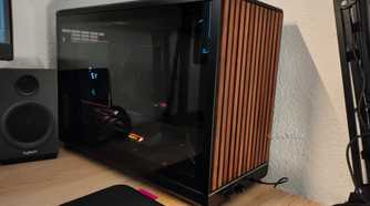An ITX PC tower stands next to a PC speaker.