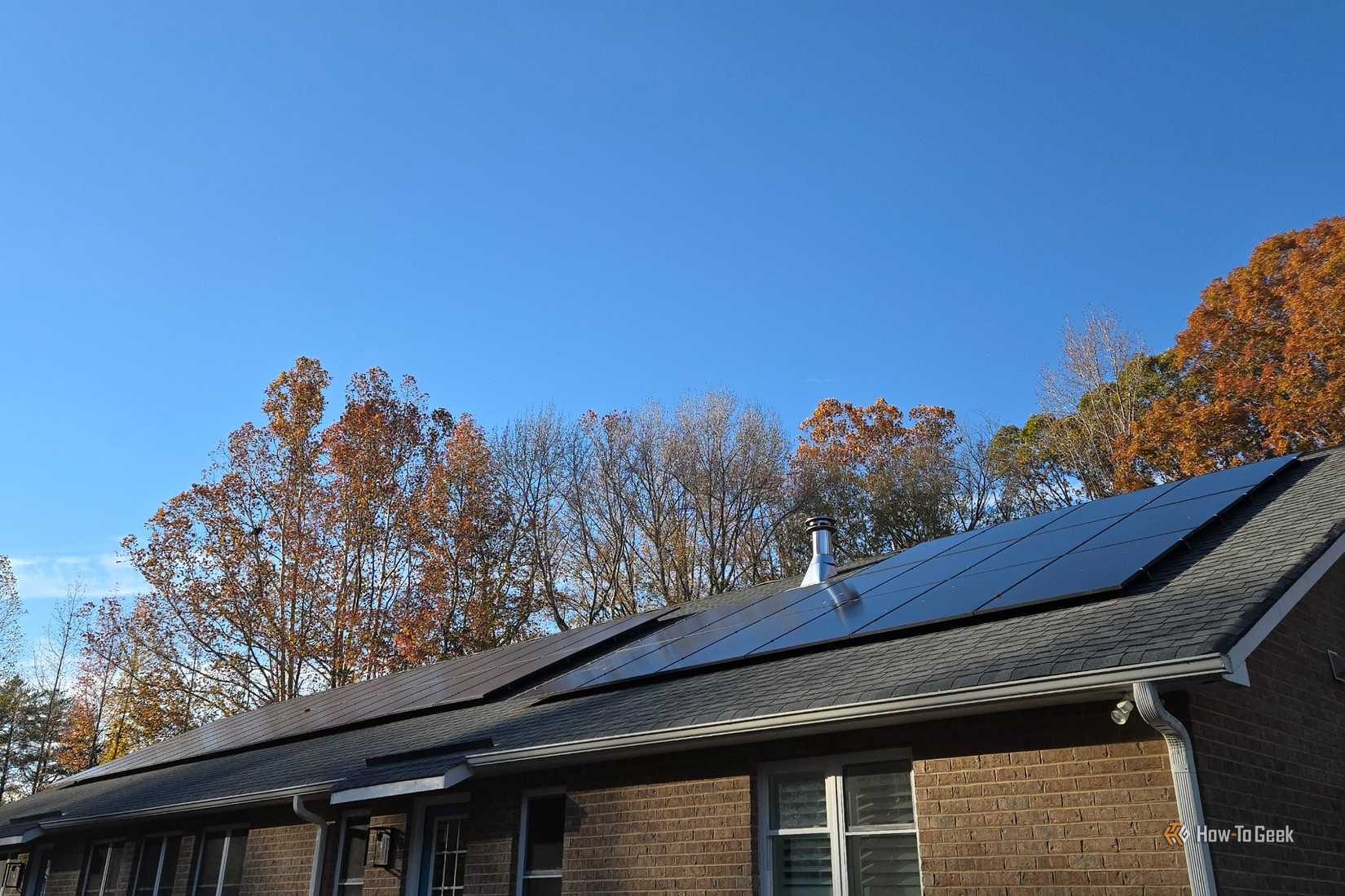 Two solar panels on the roof of a brick house.