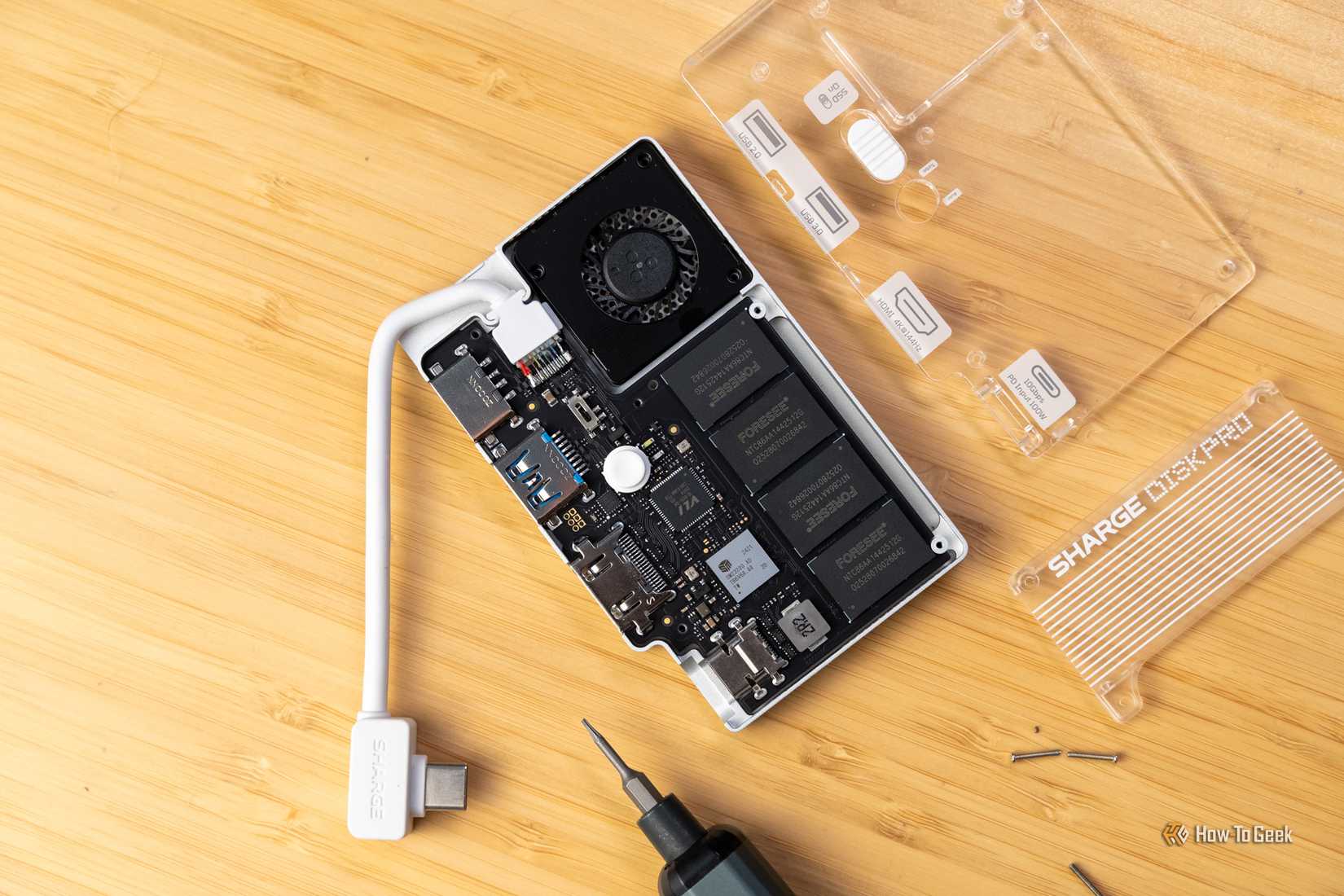A closer overhead view of the Sharge Disk Pro internals with the clear casing and screws removed on a wooden surface.
