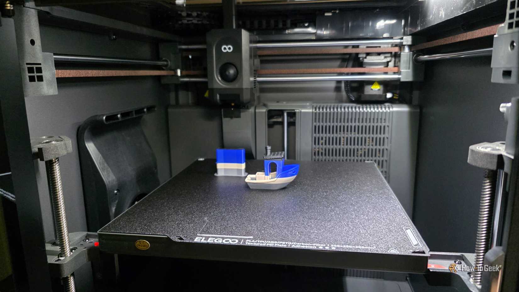 A multicolor benchy boat sits inside a 3D printer.