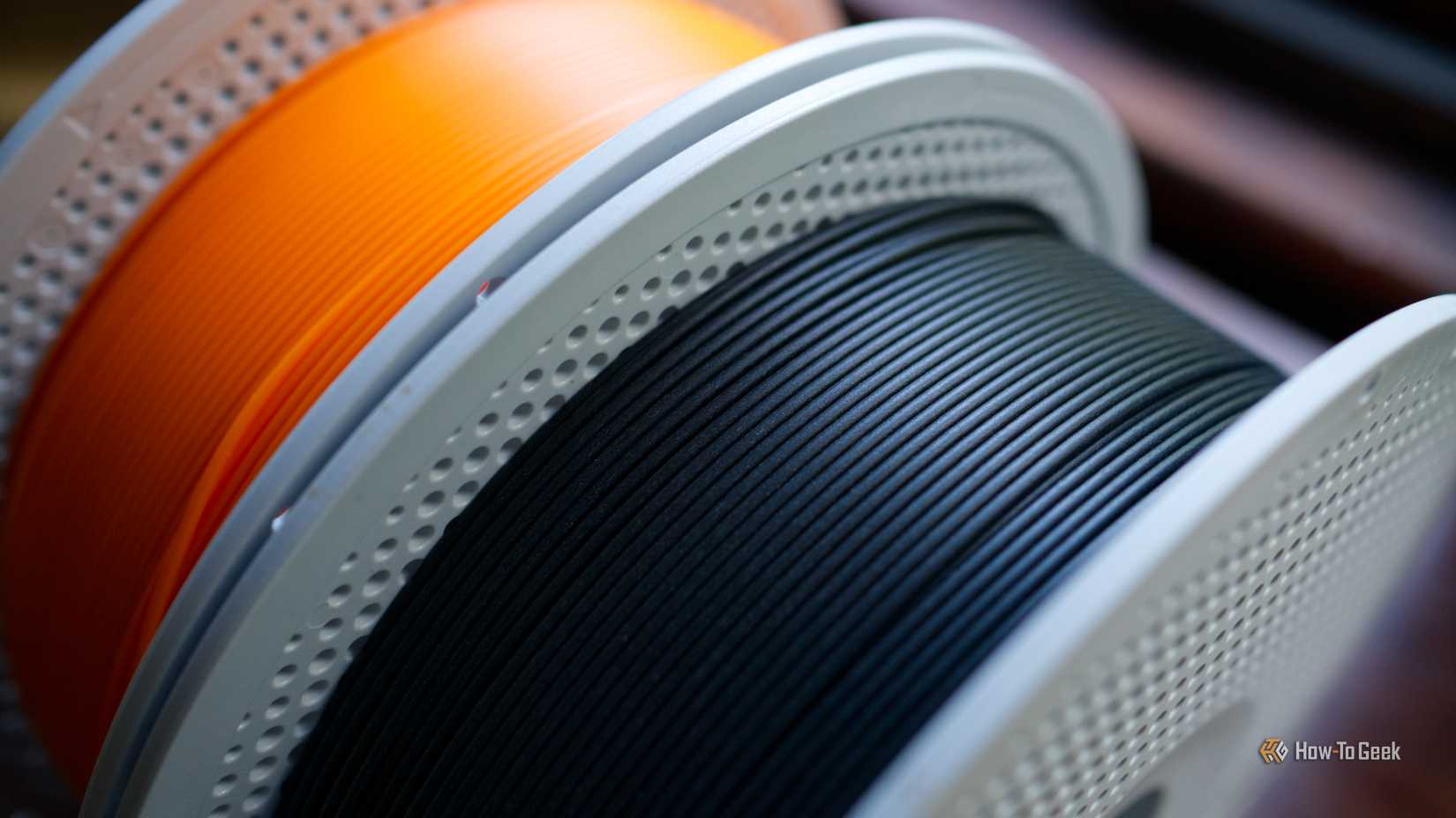 One roll of matte black PLA and basic orange PLA 3D printer filament.