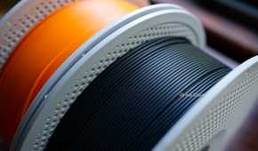 A roll of black PLA matte and basic PLA orange 3D printer filament.