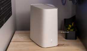 A white AT&T BGW320 Wi-Fi 6 router on a wooden shelf between two desktop towers.