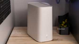 A white AT&T BGW320 Wi-Fi 6 router on a wooden shelf between two desktop towers.
