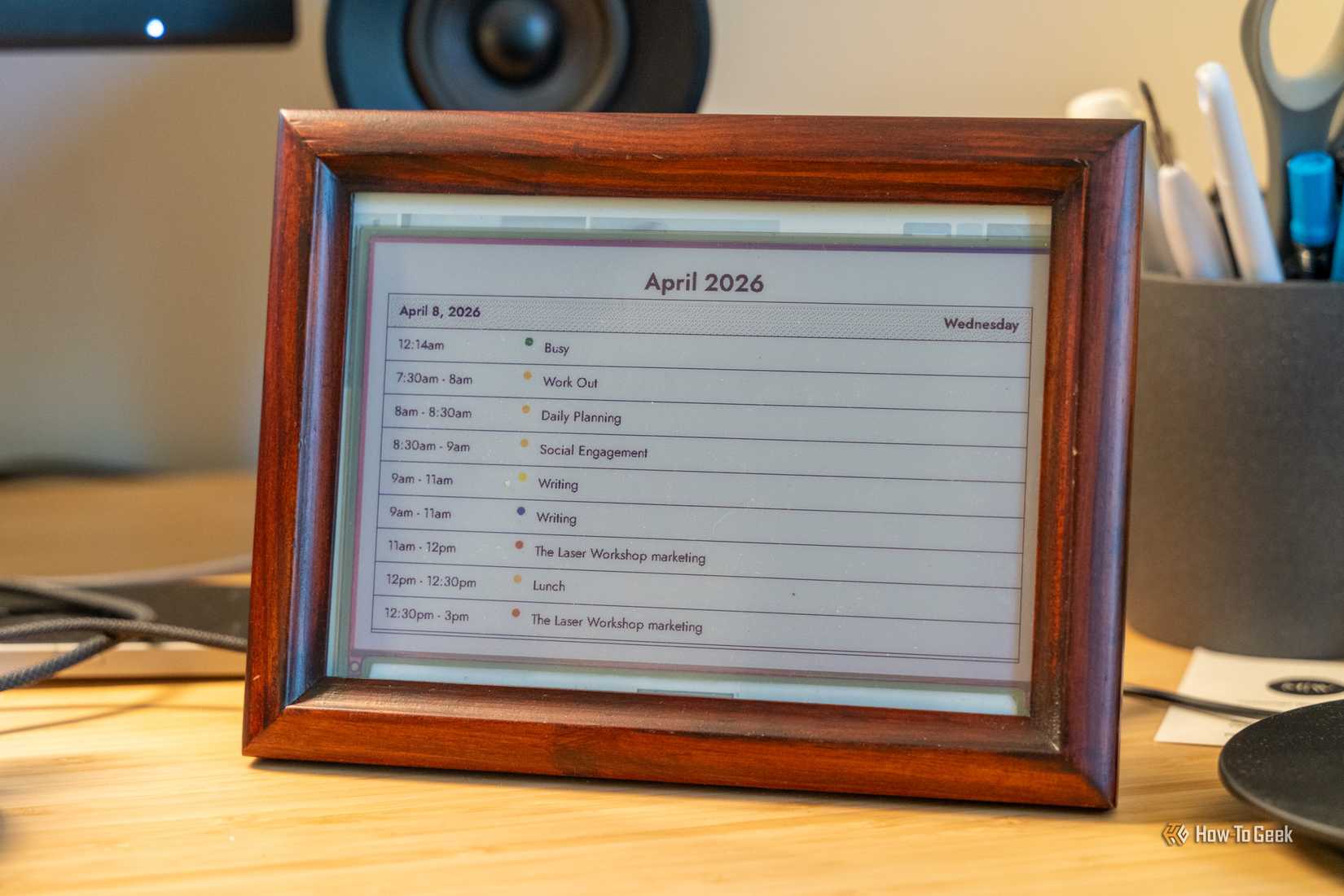 An eInk display powered by a Raspberry Pi showing a day's calendar view in a picture frame on a desk.