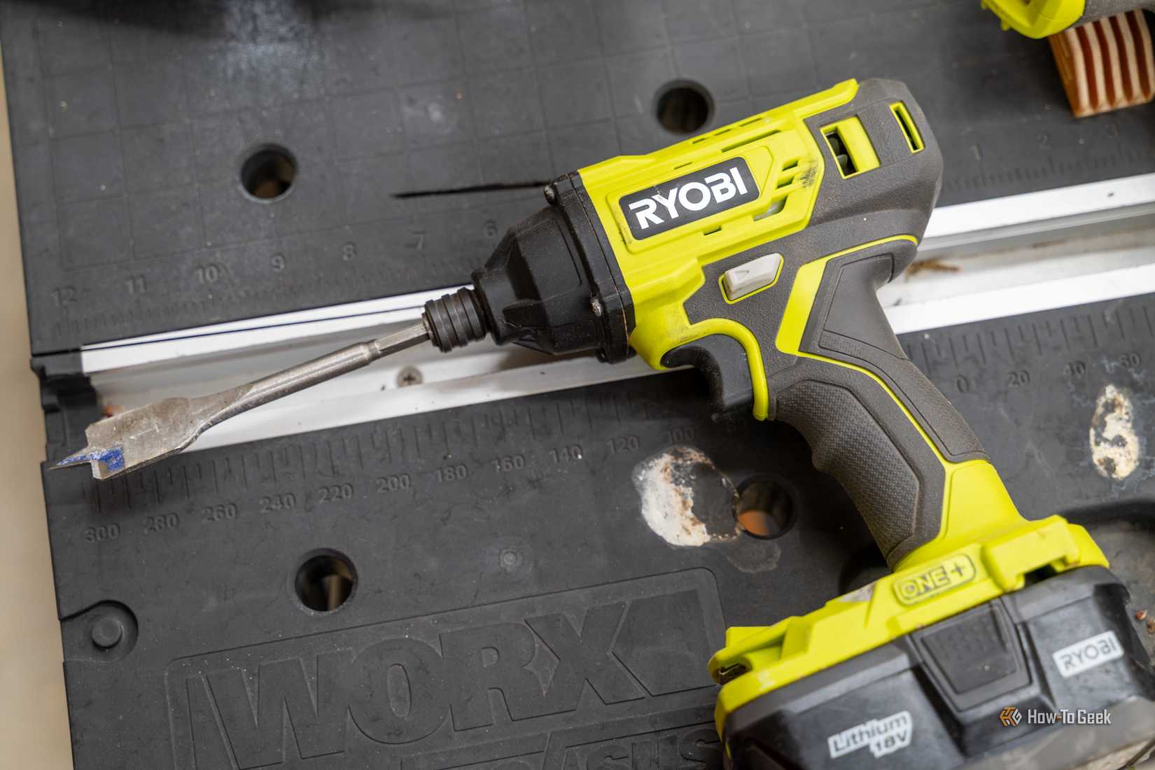 Close-up of a Ryobi ONE Plus 18V impact driver with a spade bit attached.