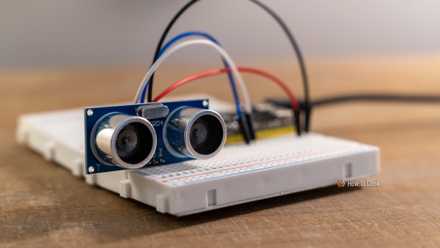 Close-up of an HC-SR04 ultrasonic sensor wired to an ESP32 development board on a breadboard.