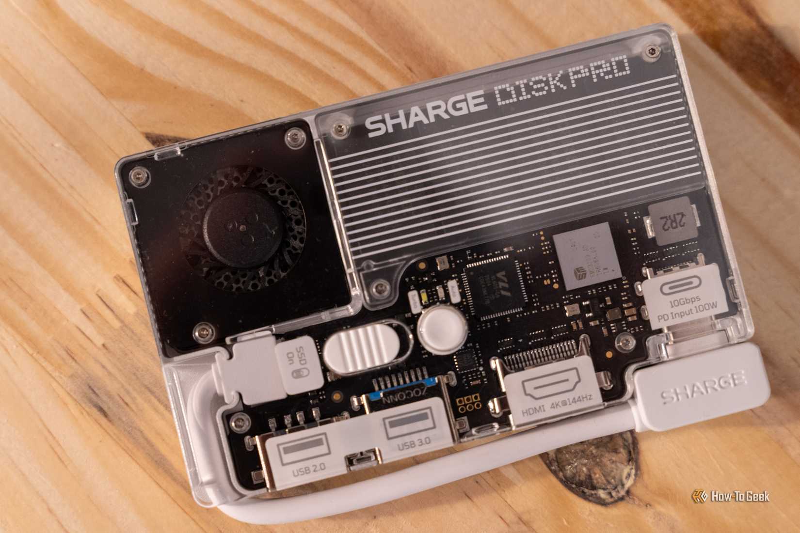 Close-up of the Sharge Disk Pro on a wooden surface with a cable connected to the USB-C port.