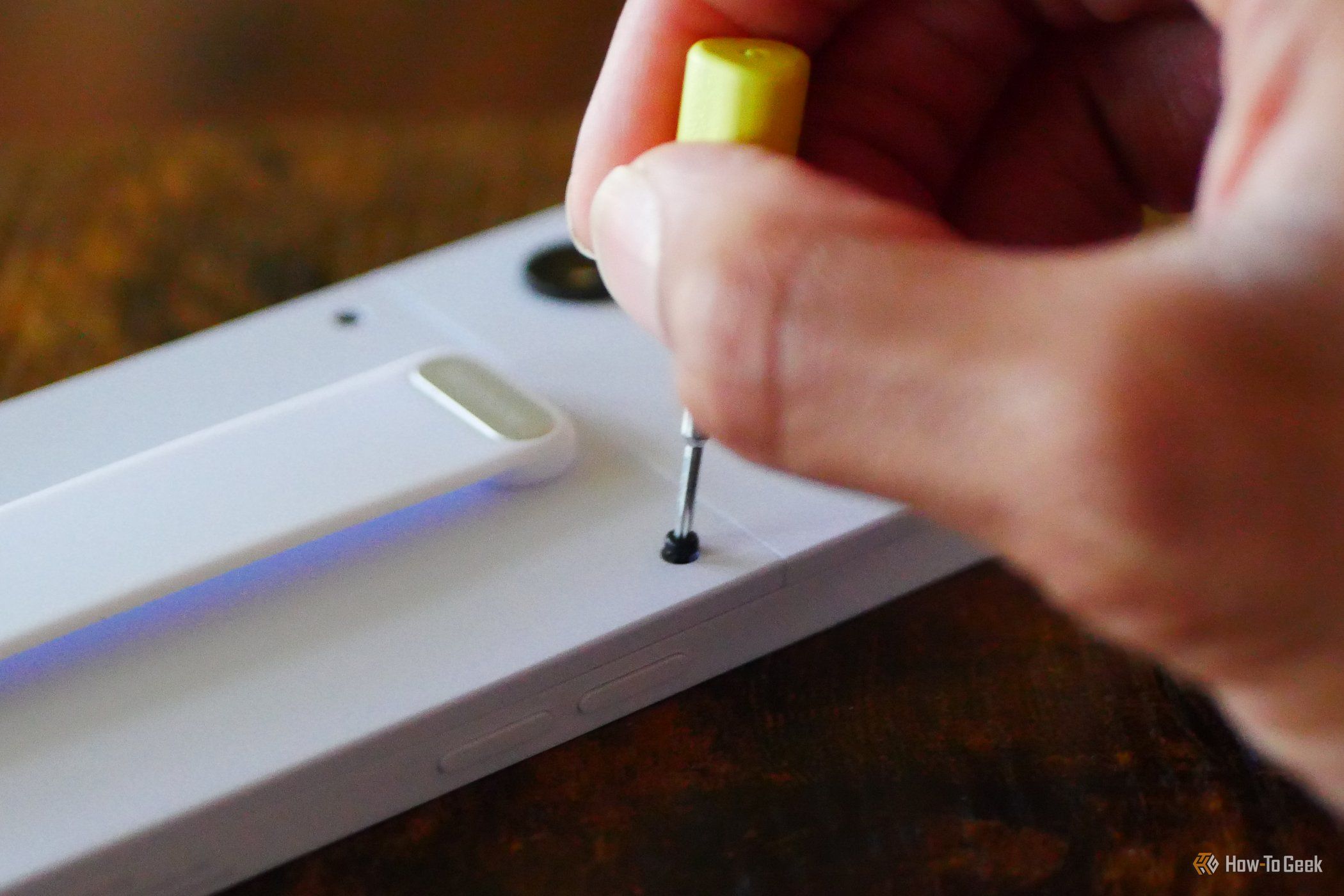 Hand removing a screw from a Fairphone 6 using the included screwdriver.