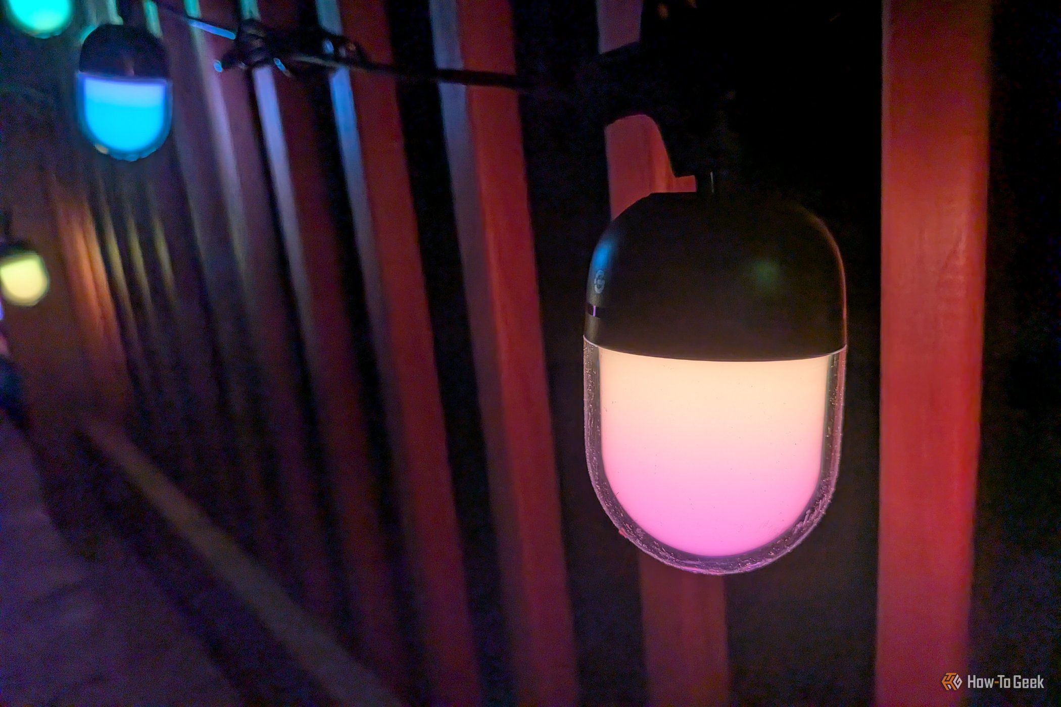 Closeup of a Govee Outdoor Chromatic String Lights bulb glowing pink.