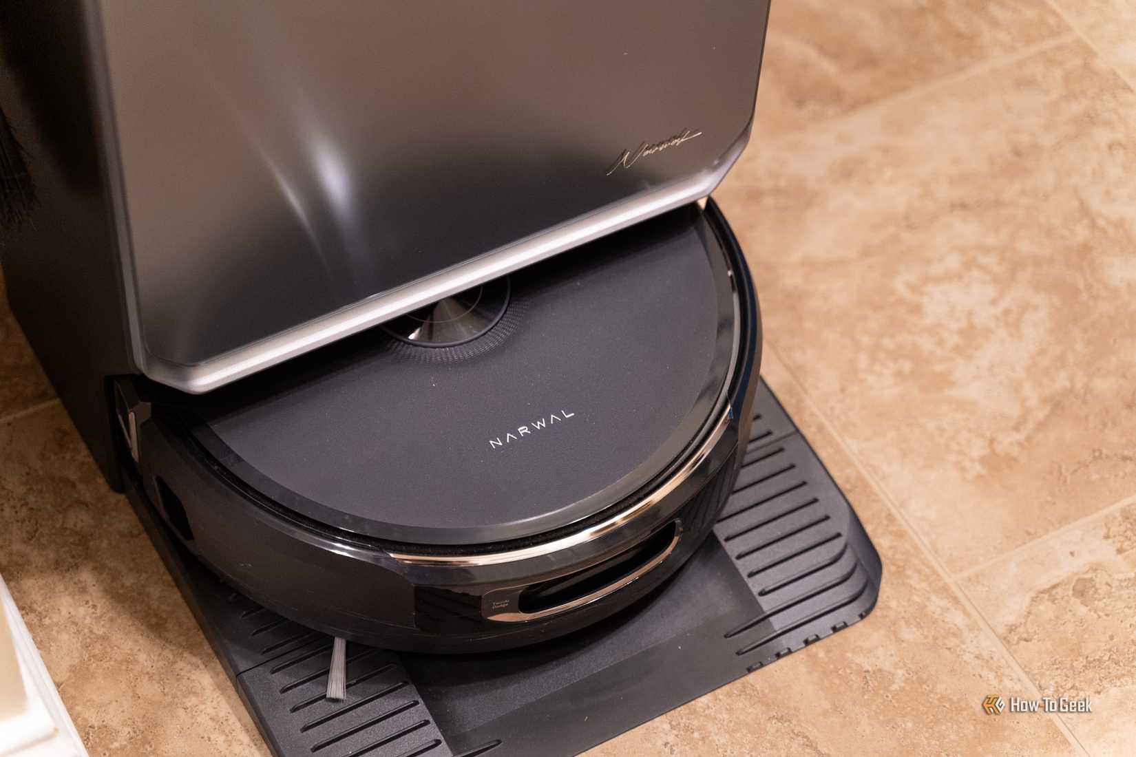 The Narwal Flow 2 robot vacuum sitting partially docked in its base station.