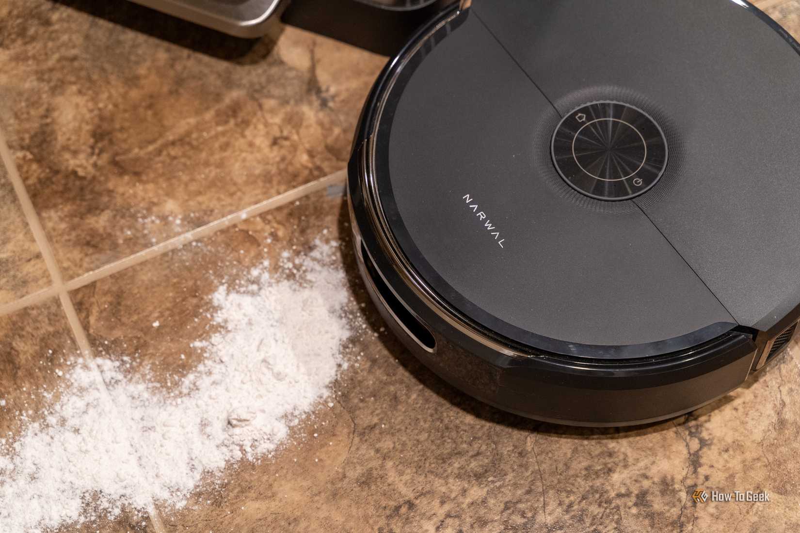 Top view of the Narwal Flow 2 robot vacuum approaching spilled flour on tile.