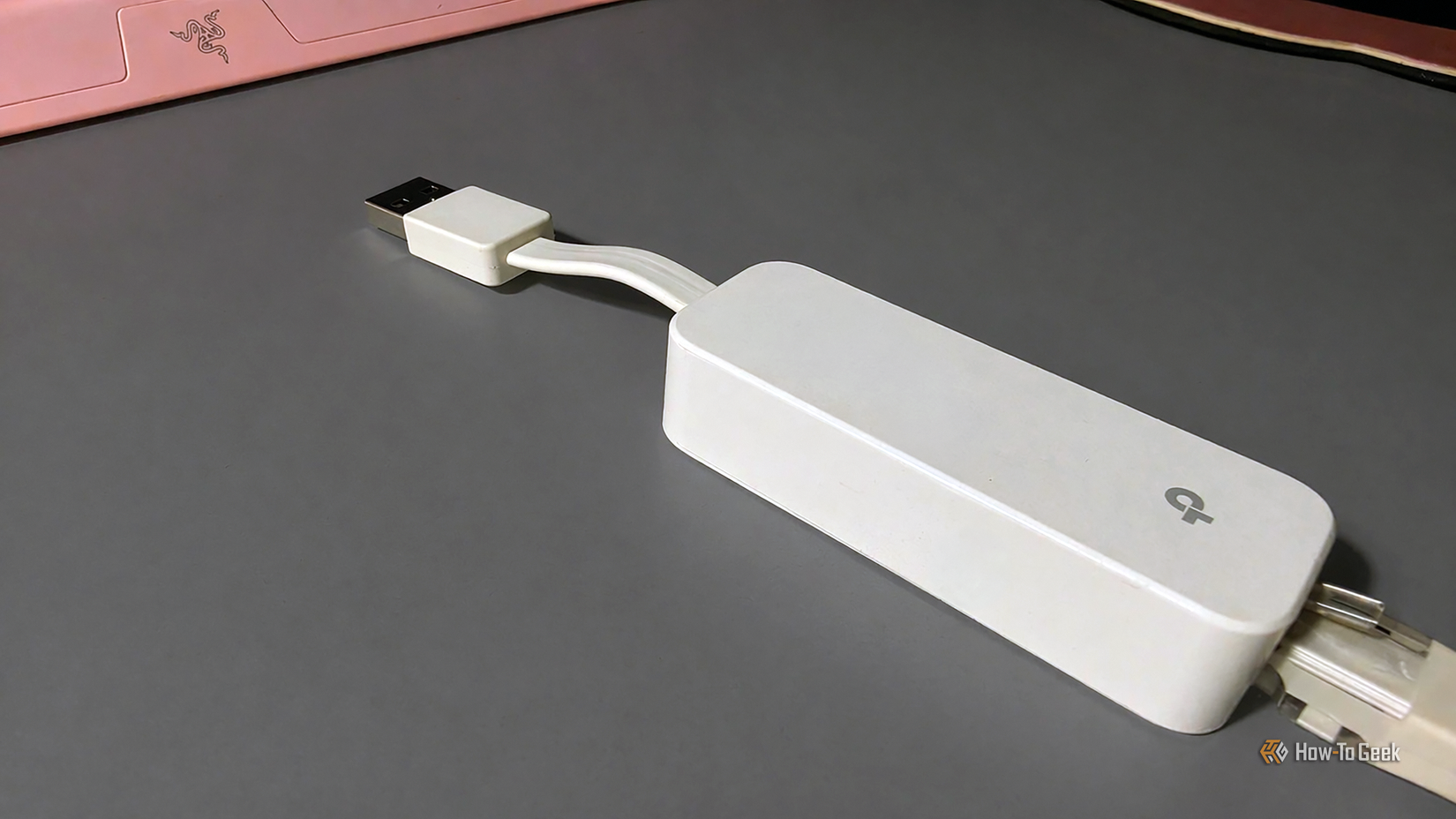 A TP-Link Ethernet to USB adapter on a dark desk.
