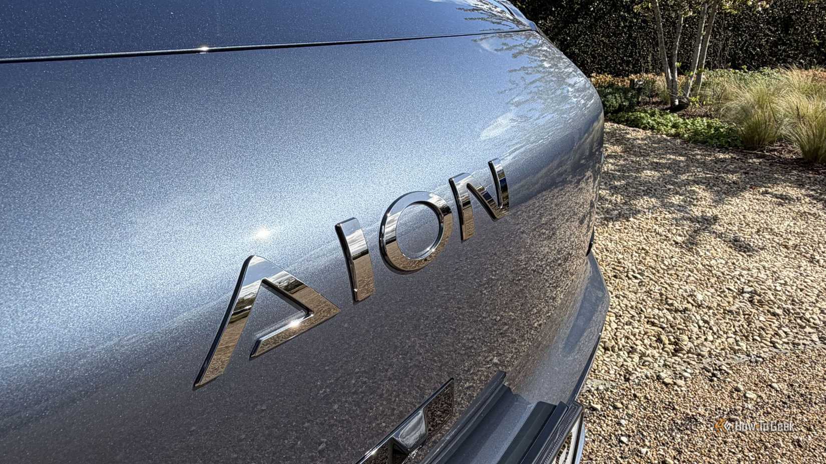 Close-up shot of the 'AION' badge on the front of a gray AION V.