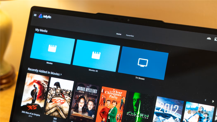 Angled laptop view of Jellyfin home screen with recently added movie rows.