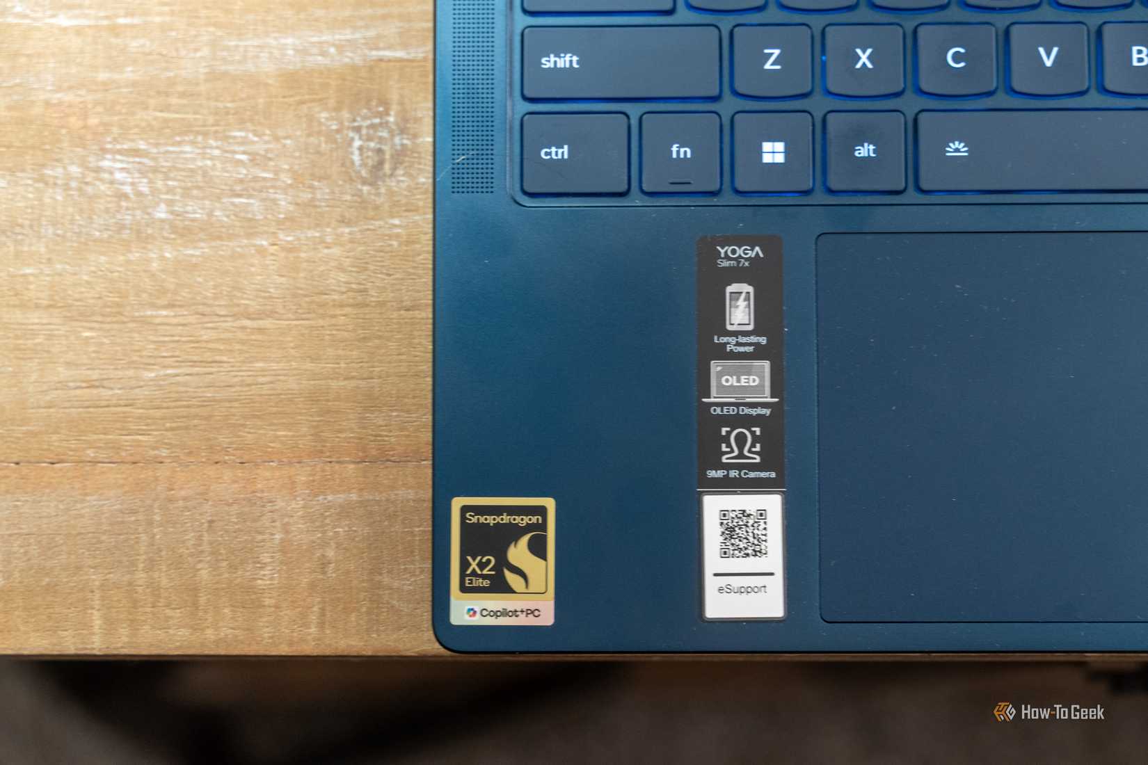 Close-up of the Lenovo Yoga Slim 7X palm rest stickers for Snapdragon X2 Elite and OLED features.