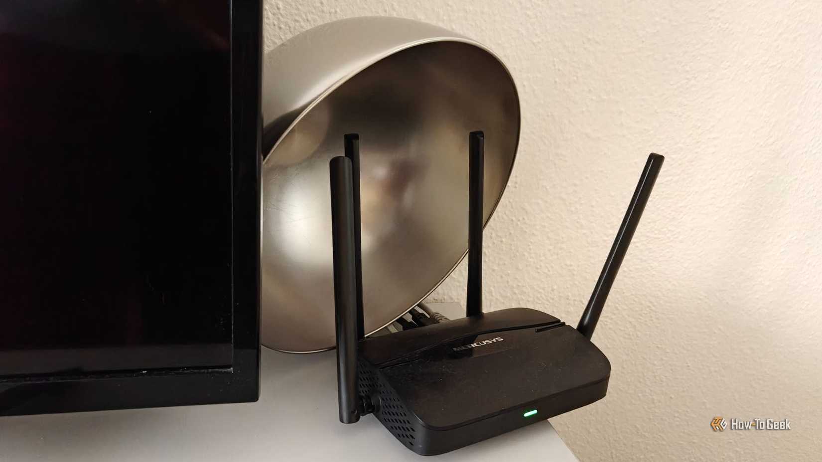 A Wi-Fi router with a stainless steel bowl behind it.