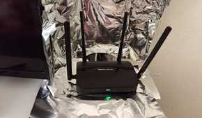 A Wi-Fi router sitting inside a partial Faraday Cage made of aluminum foil.