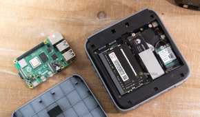 Open ACEMAGIC M5 mini PC internals beside a Raspberry Pi 4B and removed bottom cover.