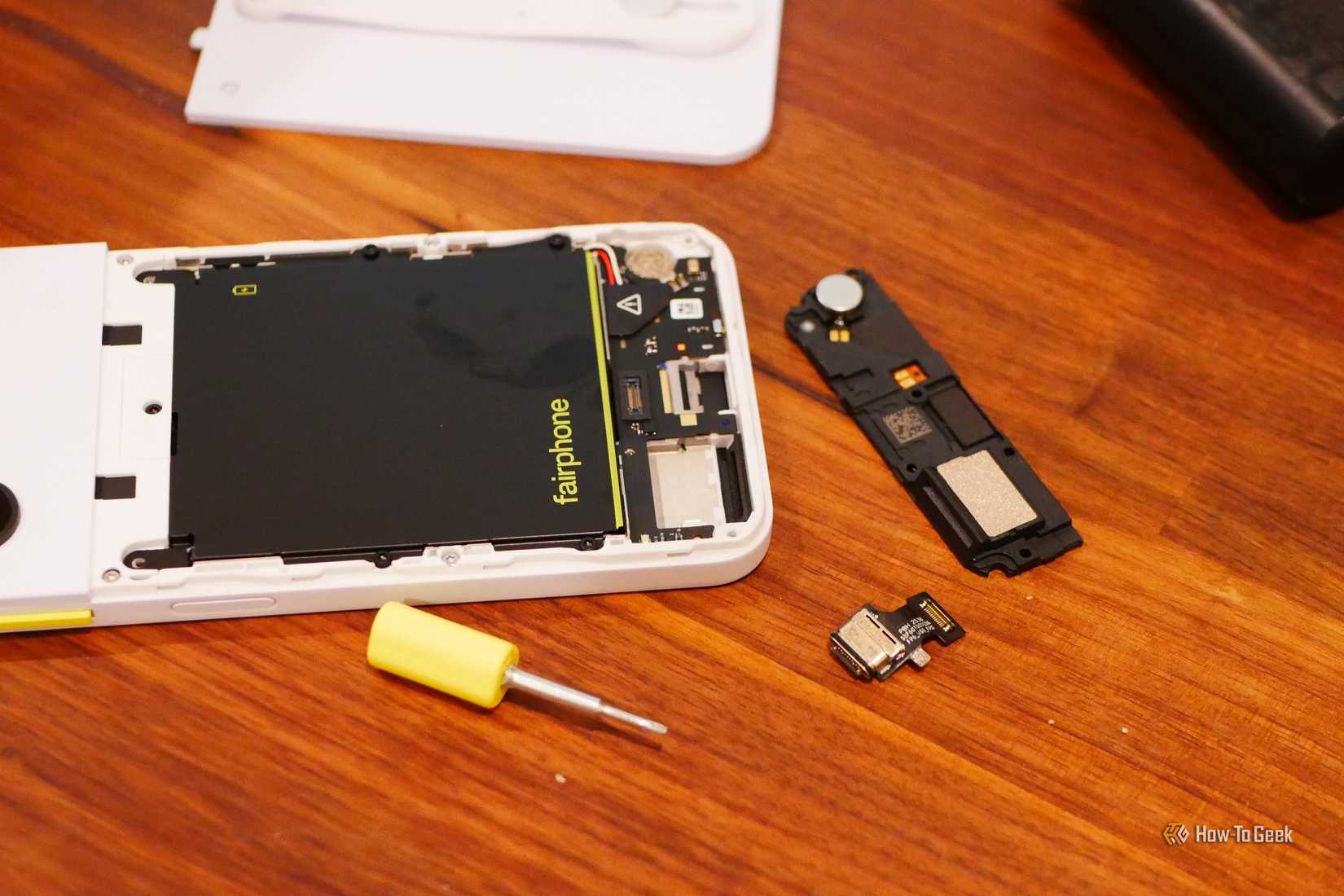 Fairphone 6 with rear panel and some components removed along with a screwdriver.