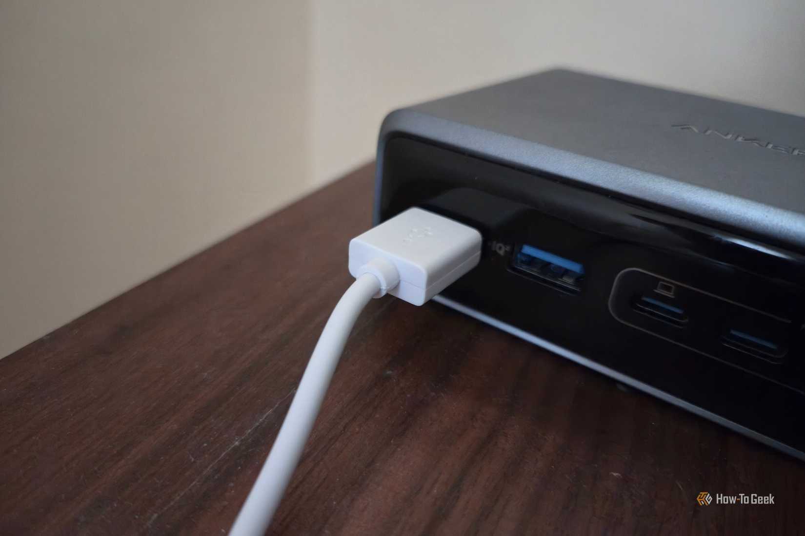 White USB cable plugged into an Anker charging station.