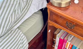 A NFC tag stuck to a nightstand next to a bed.