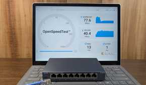 A network switch and a DIY Ethernet cable laying on a laptop showing a speed test.