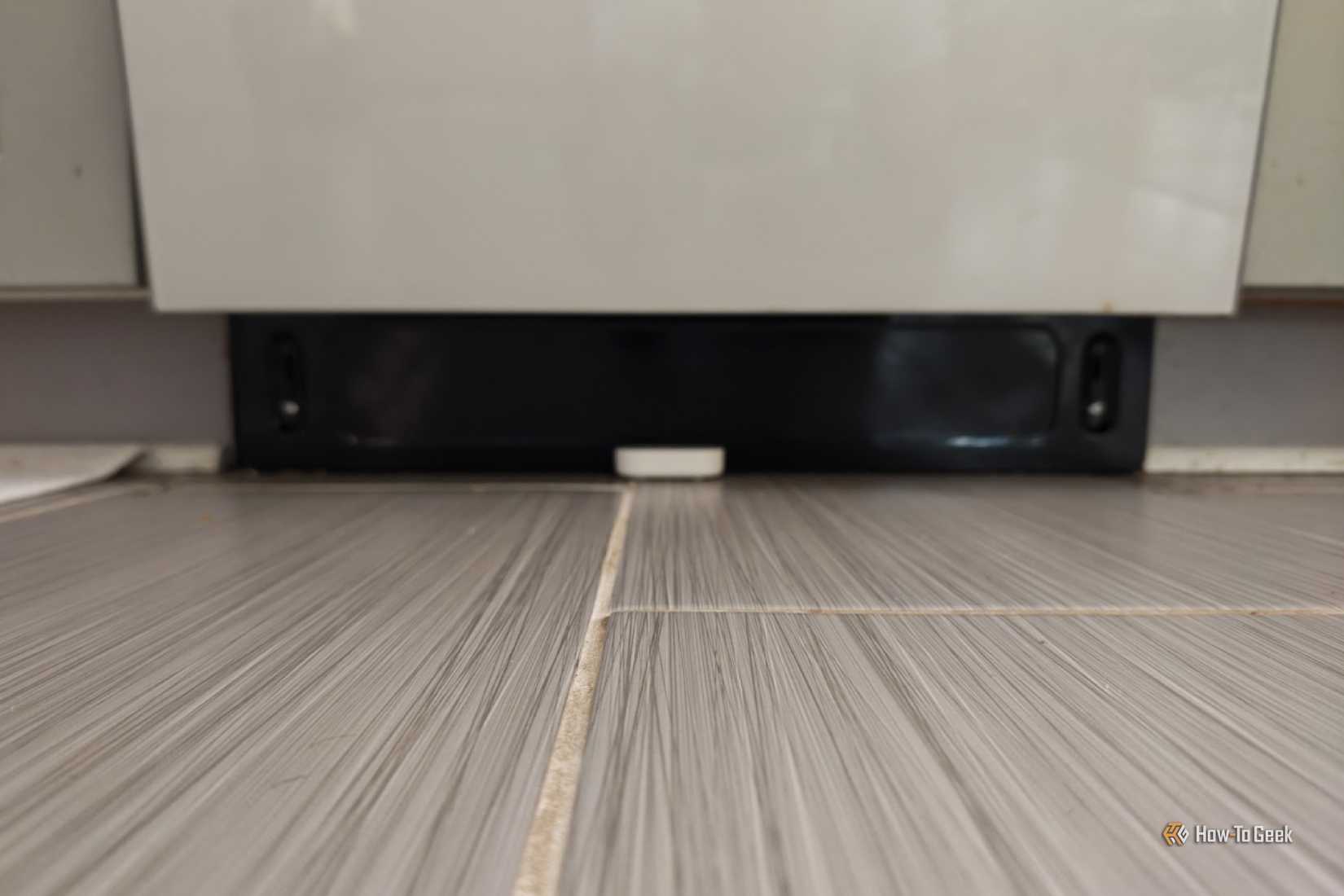 A far away view of an IKEA KLIPPBOK water sensor underneath a dishwasher.