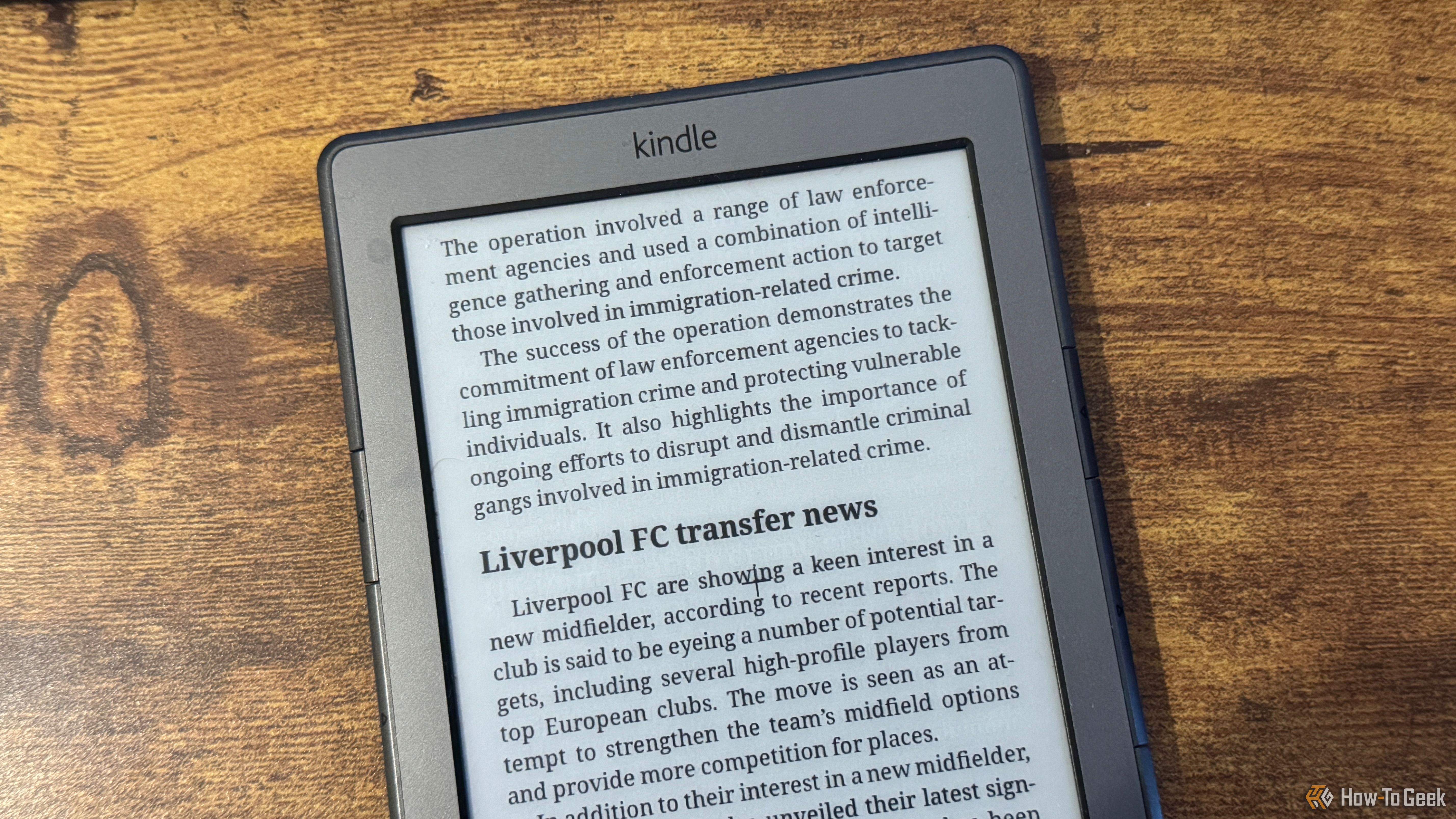 A close up of a Kindle 4 showing the end of the UK immigration crime crackdown article and the start of the Liverpool FC transfer news section.