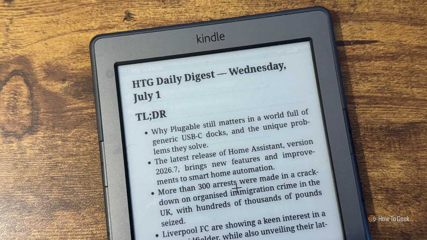 A close up of a Kindle 4 showing the HTG Daily Digest TLDR bullet list covering Plugable Home Assistant immigration crime and Liverpool FC.