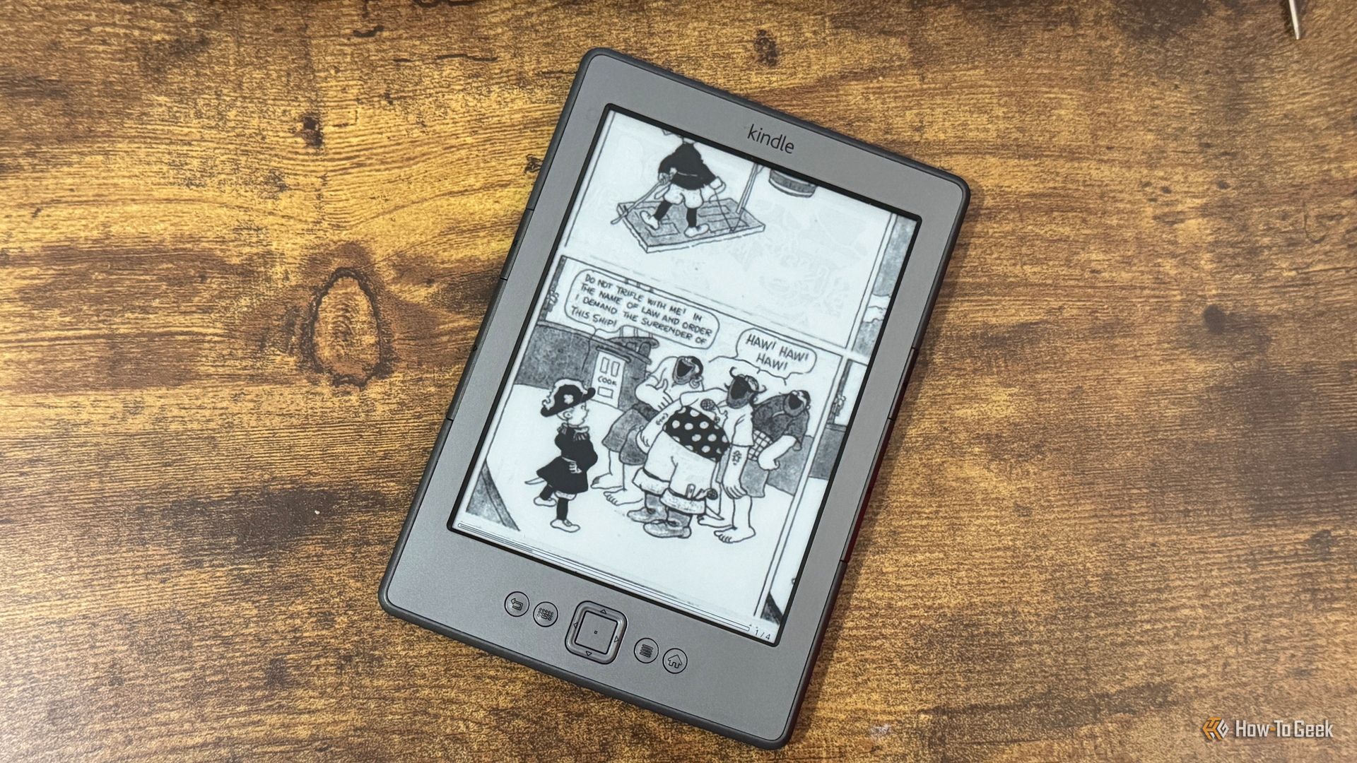 A Kindle 4 running KOReader showing a CBZ comic panel with a boy demanding the surrender of a pirate ship while pirates laugh.
